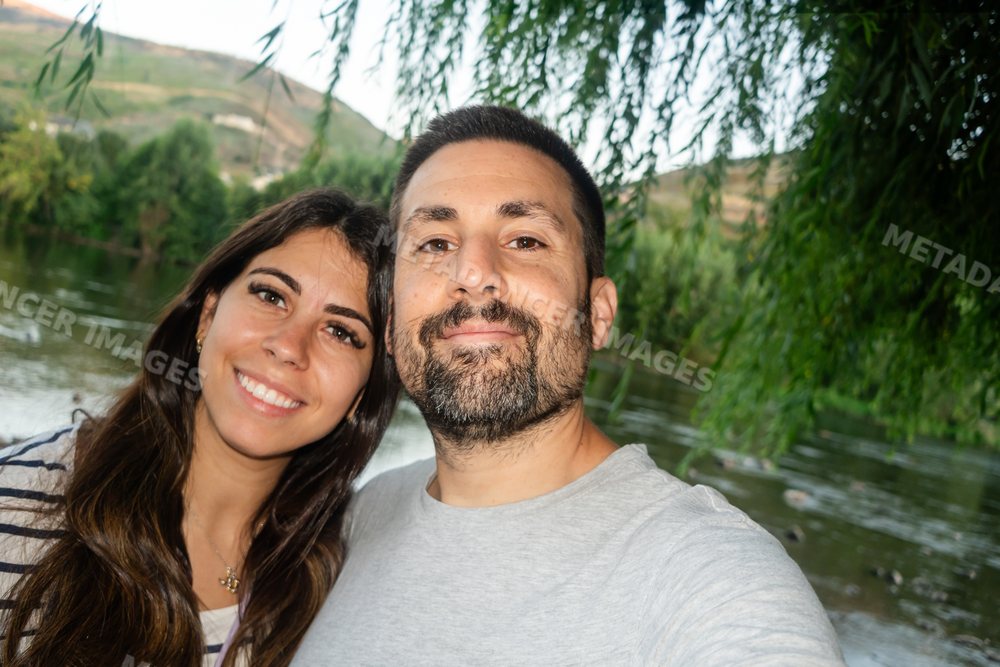 Couple happily taking a selfie outdoors near a riverside in Spain