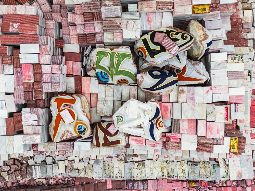 Aerial view of large stacked stones painted with colorful Tibetan script forming a dense outdoor pattern in Jiana Mani City, Xinzhaia, Qinghai Province, People's Republic of China.