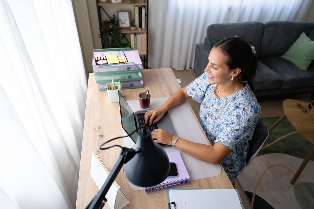 Woman working on a laptop at a home office desk, telecommuting, Spain.