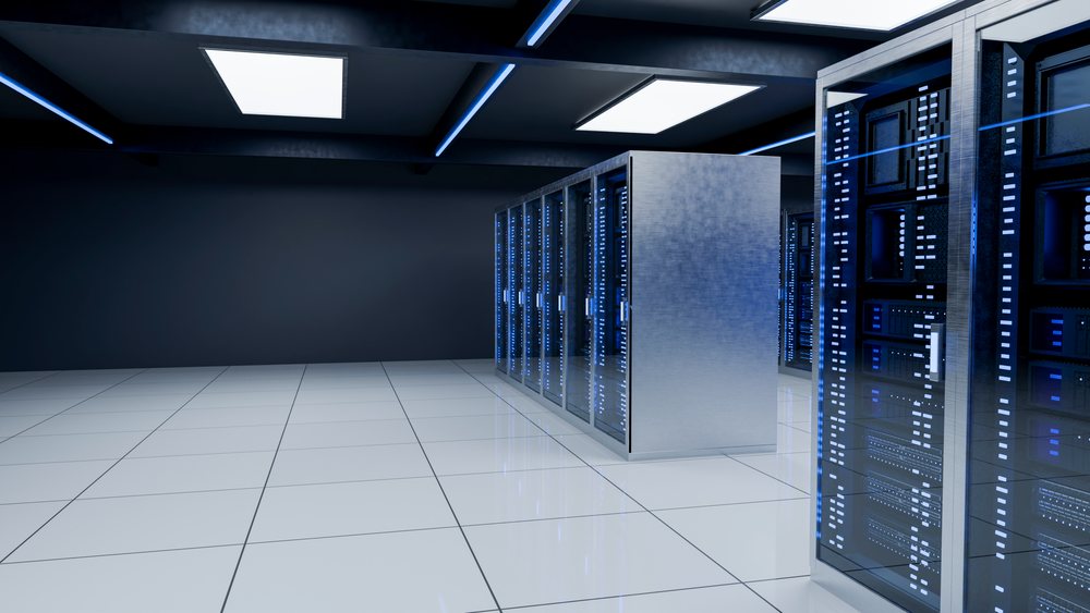 Modern data center room with server racks and blue indicator lights on a tiled floor beneath illuminated ceiling panels.