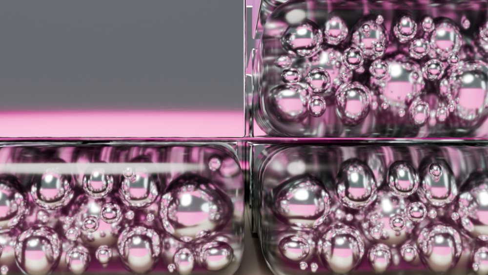 Close-up macro view of transparent bubble wrap showing multiple air bubbles and pink reflections on its textured plastic surface.