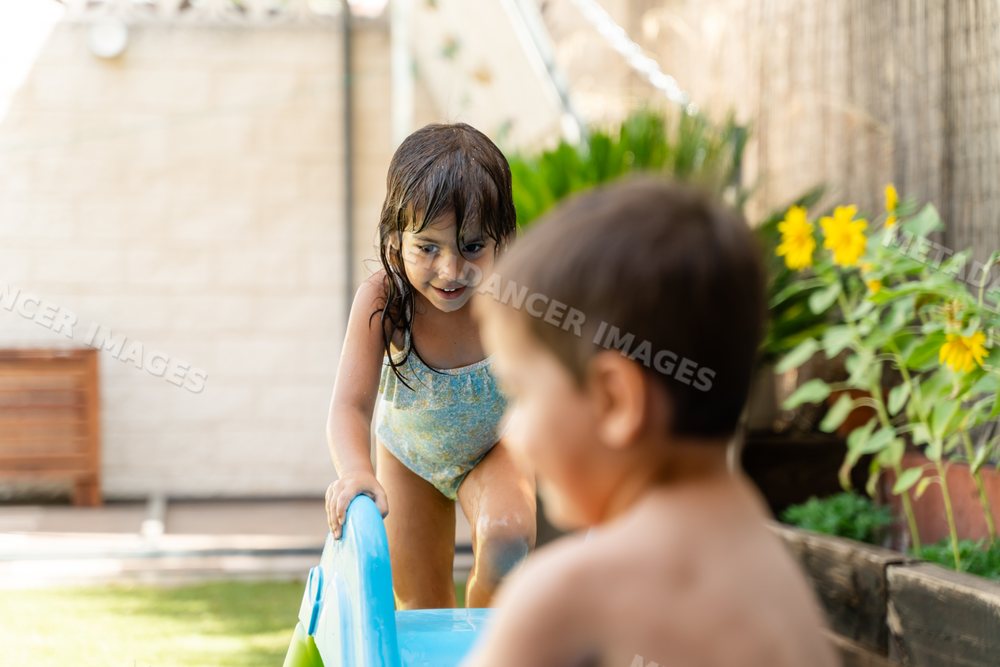 A young white girl climbs a water slide playing outdoors