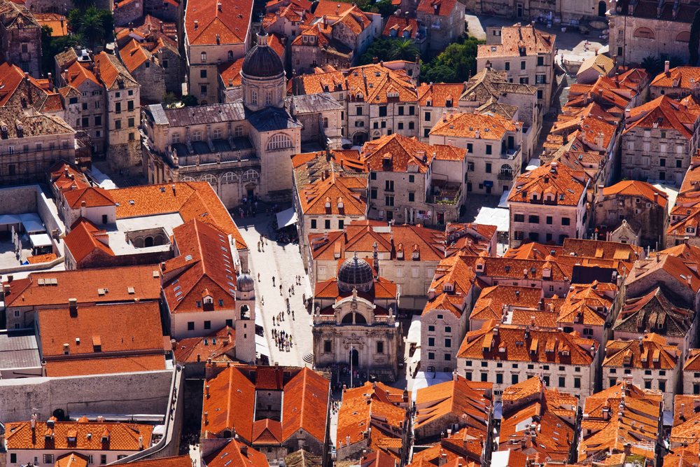 Aerial view of the Old City of Dubrovnik showing historic buildings with red tile roofs and crowds on the streets.