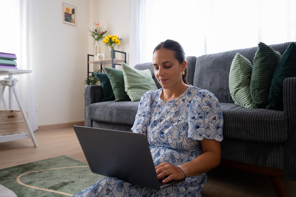 Woman using a laptop while sitting on the floor in a modern living room, telecommuting, Spain.
