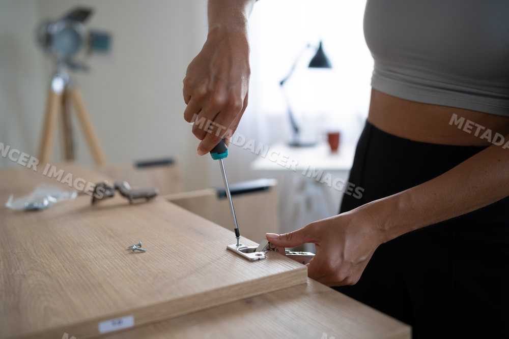 White Person assembling furniture by attaching a metal hinge