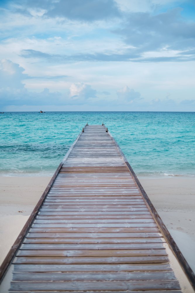 A wooden pier stretches over turquoise ocean waters
