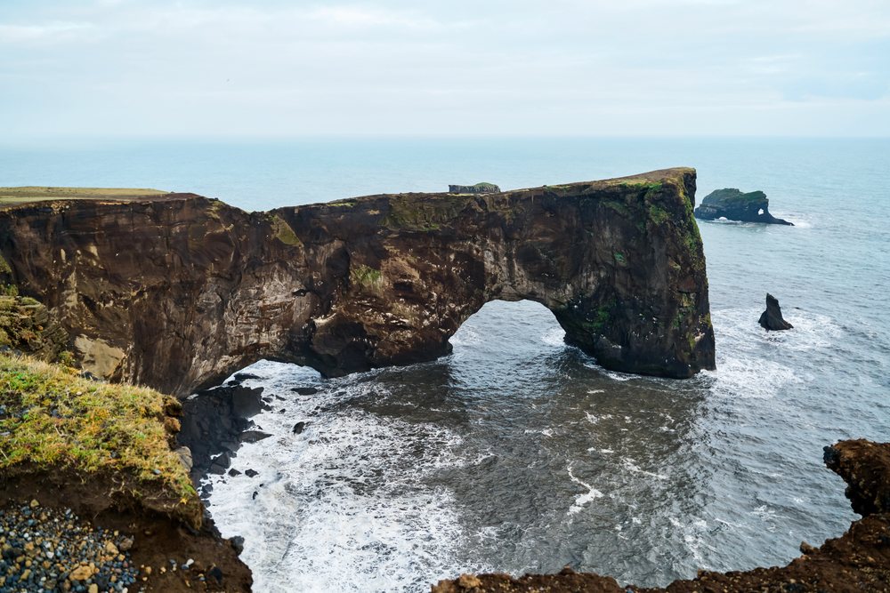 Natural rock arch stands over ocean waves along Iceland's rugged