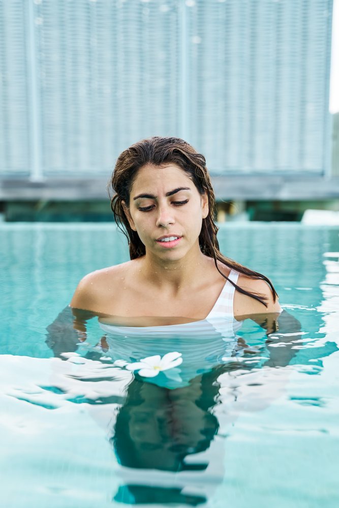 White Woman relaxing in a swimming pool with a floating flower