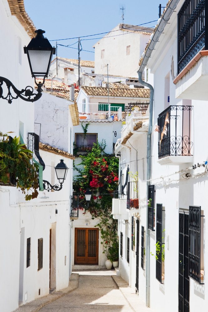 Narrow street with white buildings and flowers, Valencia, Spain.