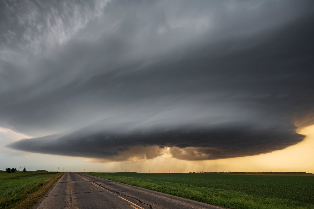 Supercell cloud base with visible RFD Cut over a rural road and green field during sunset lighting, Storm Chasing, Marion, North Dakota, USA.