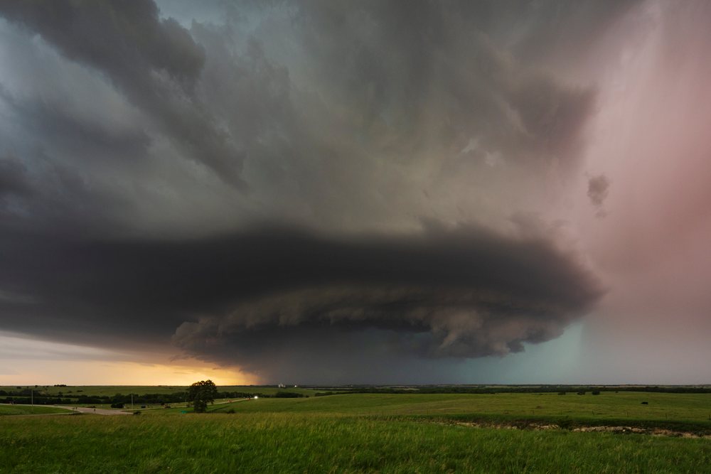 Supercell storm with dark cumulonimbus clouds over a grassy rural landscape at evening, Storm Chasing, Weather, Environmental Issues, Herrington, Kansas, USA.