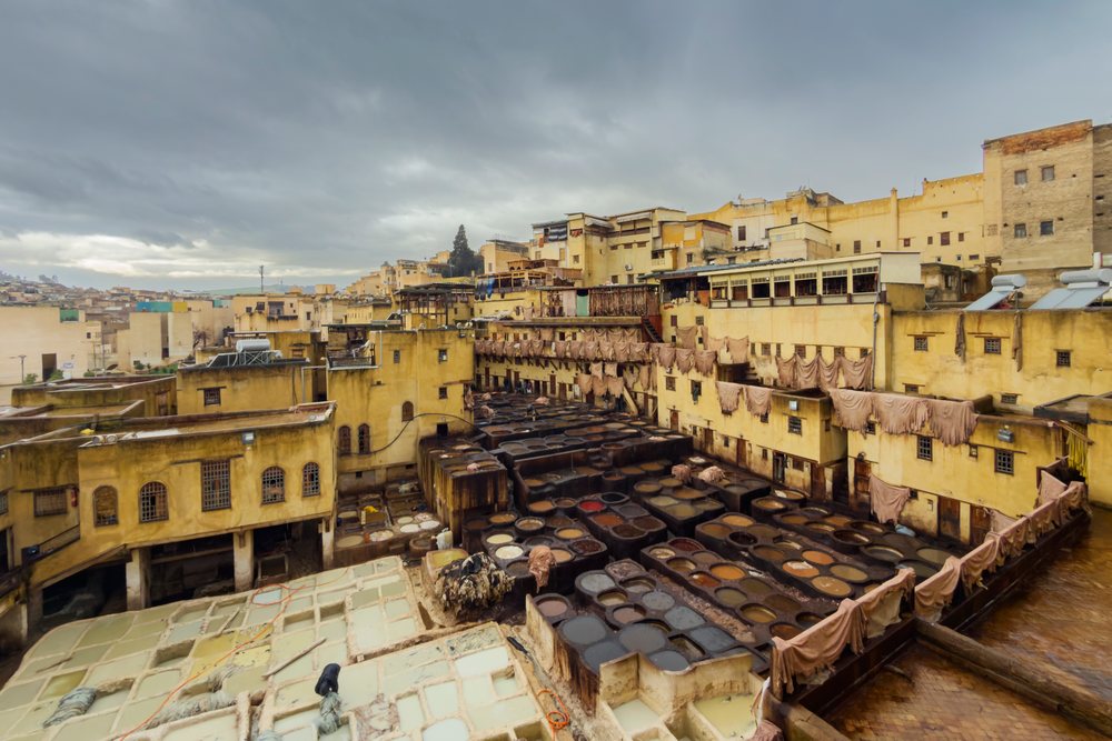Outdoor leather tanning vats and hanging hides at Chouara Tannery, Morocco under pouring rain in historic urban setting, Landscape, Lifestyle, Fes, Fes-Meknes Administrative Depart.