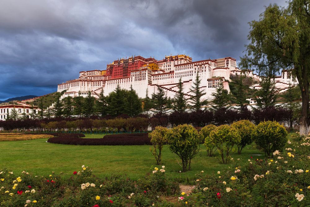 Potala Palace on a hilltop at Sunrise with a garden of flowers, shrubs, and trees, Lhasa, Autonomous Region of Tibet.