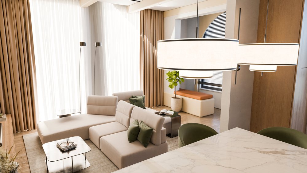 Bright modern living room featuring a beige sectional sofa with green pillows, a metallic coffee table with books and reed diffuser, and a marble countertop under hanging lights.