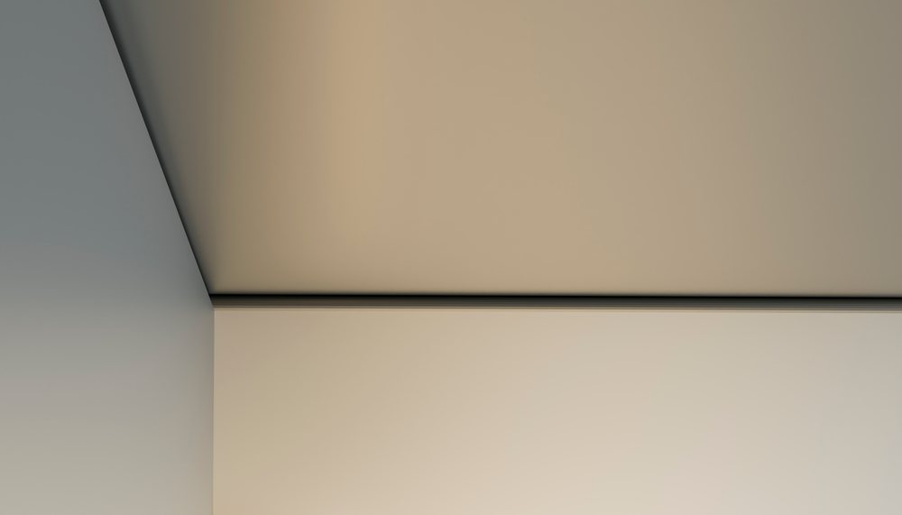 Corner of an interior room showing the junction of beige and gray painted walls and ceiling with smooth surfaces.