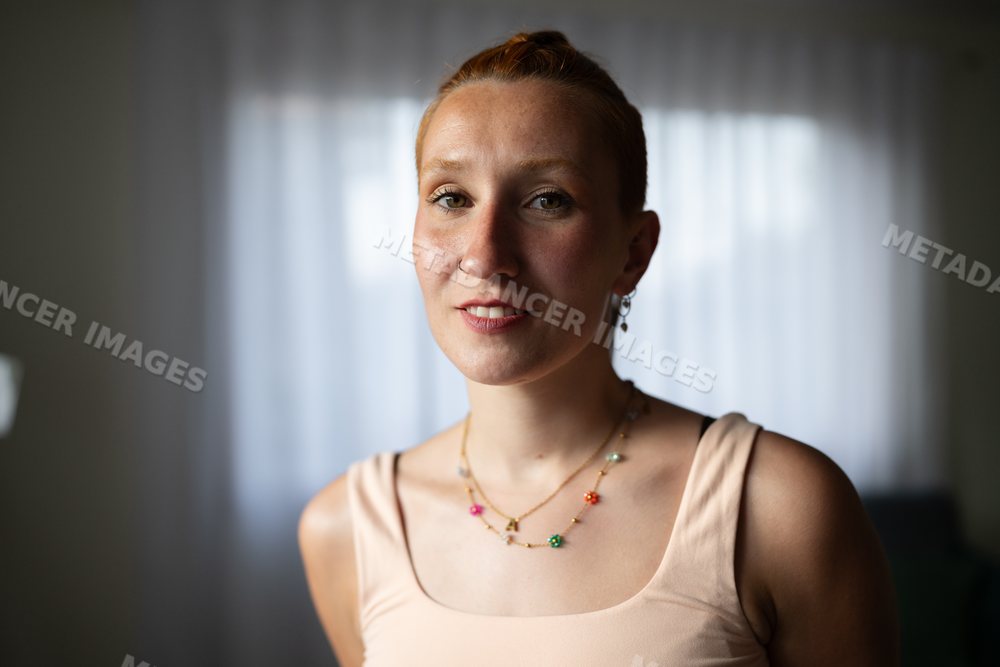 A white woman smiles softly at home in Galicia, spain wearing jewelry