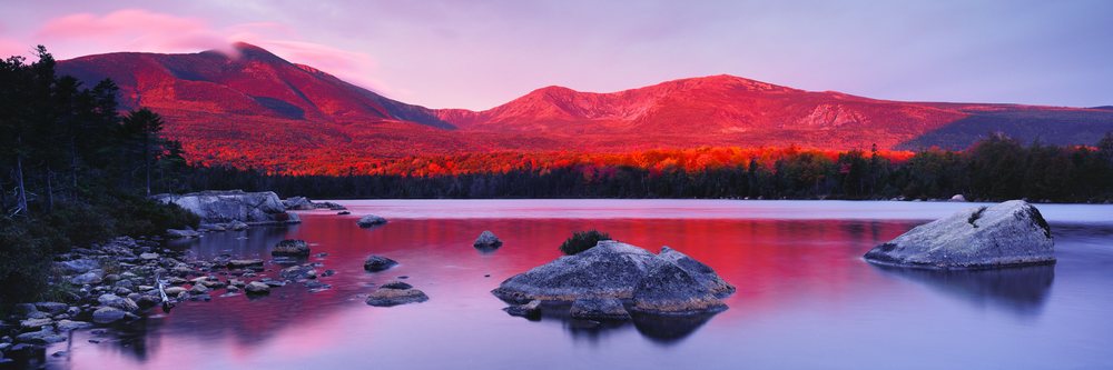 Mount Katahdin reflects vibrant red sunset light over calm lake waters, Mount Katahdin Baxter State Park Maine, USA.