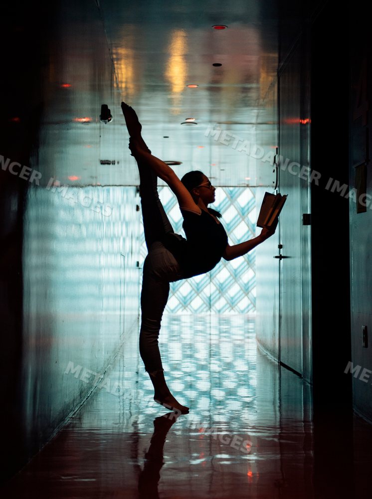 A girl stretches in a yoga pose while reading a book in a library