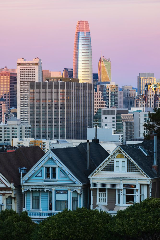 The San Francisco Skyline features Victorian Painted Ladies houses and downtown buildings at sunset with trees visible, City, Cityscapes, City Life, California, USA.