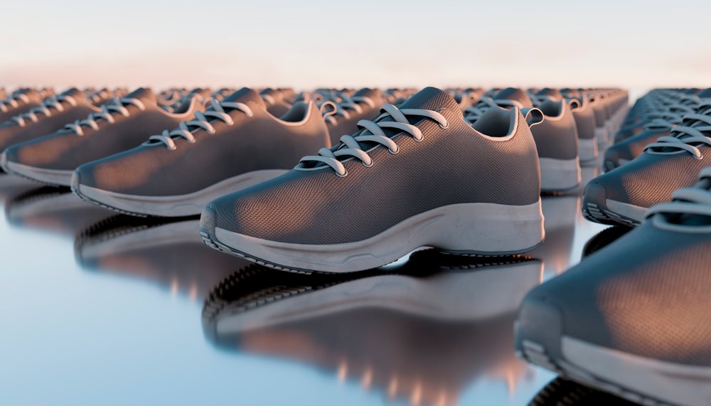Rows of gray sneakers with white soles and laces reflected on a polished surface.