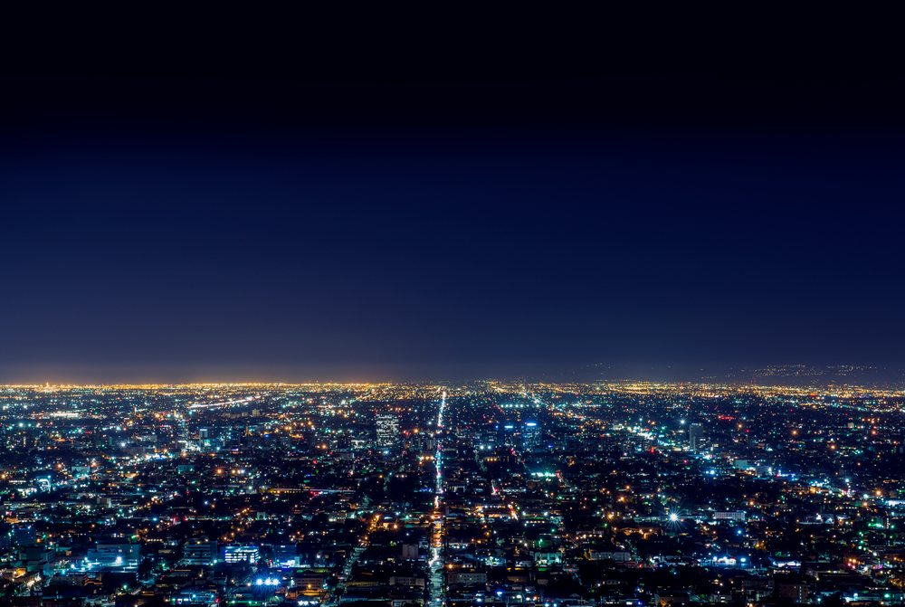 Aerial view of Los Angeles cityscape at night with illuminated streets and buildings under a clear night sky, eclipse, USA.