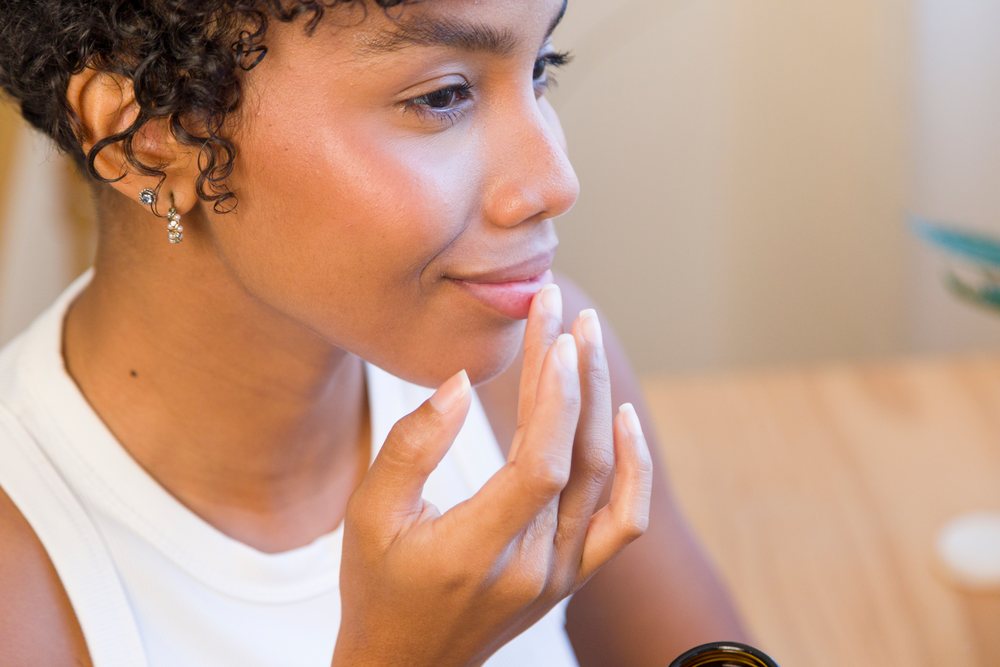 Young woman wearing earrings touches her chin in a calm indoor moment.
