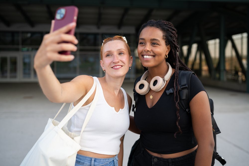 Two women take a selfie outdoors in an urban setting, Santiago De Compostela, Spain.