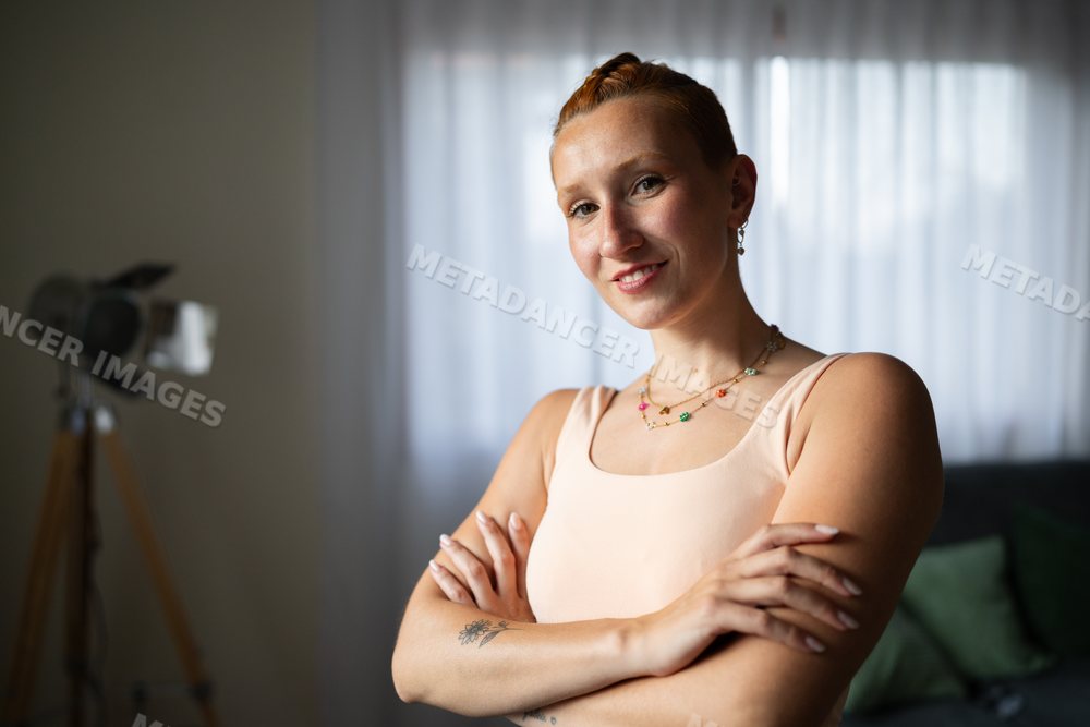 A smiling white woman confidently poses with crossed arms