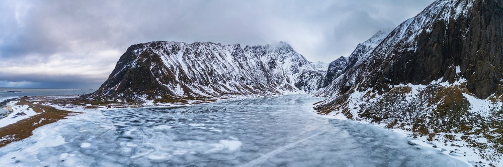 Frozen lake with ice and snow-covered mountains at Eggum Nature Reserve, Norway under an overcast sky, Landscape, Lofoten.