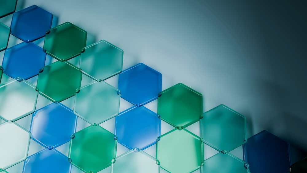 Hexagonal translucent blue and green tiles overlap to form a geometric wall pattern in a modern interior.