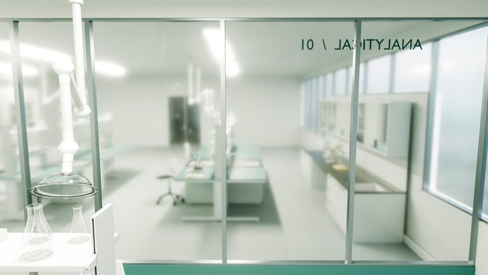 Empty clean laboratory with glass doors, workstations, laboratory equipment, and fluorescent lighting in a clinical research facility.