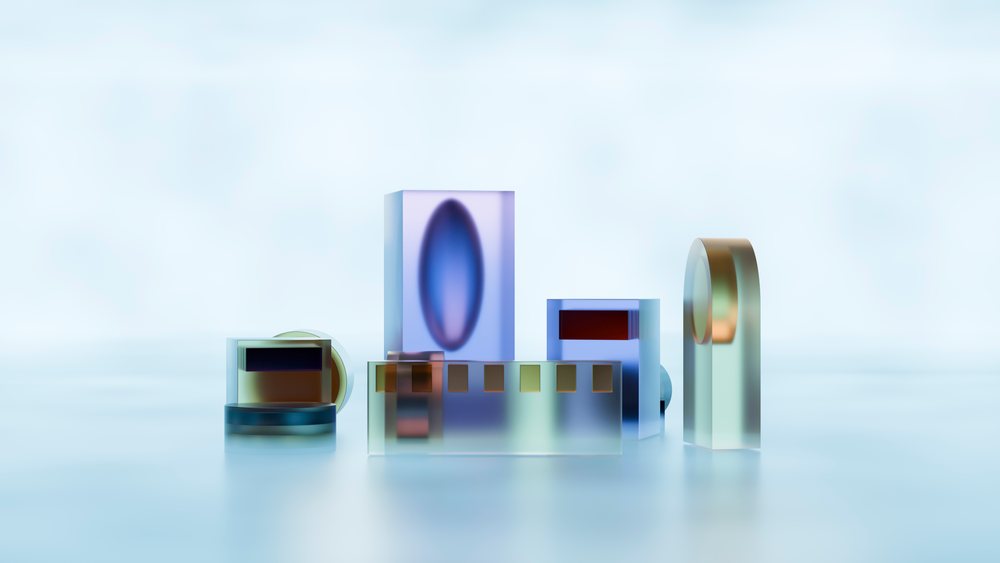 Abstract geometric glass shapes in blue and gold tones arranged in a row on a reflective surface in a minimalistic studio setting with soft shadows.
