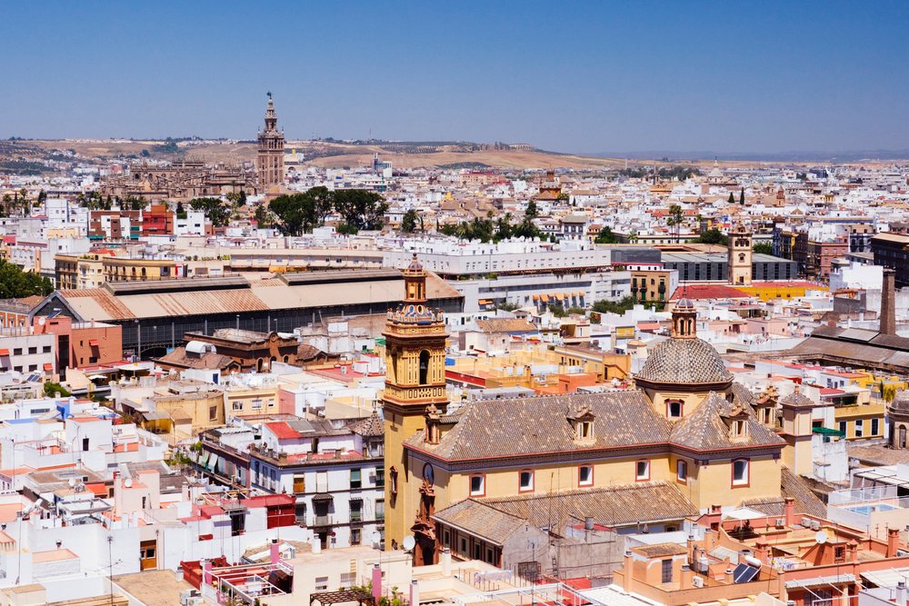 Cityscape view of Seville showing historic buildings and church towers under a clear blue sky, Andalucia, Spain.