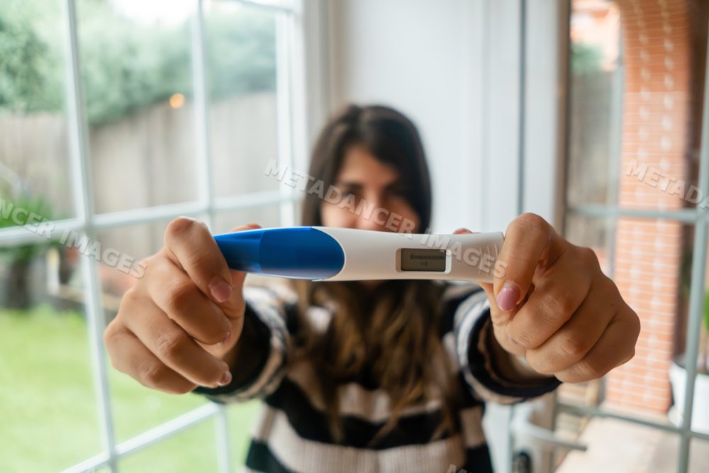 A white woman holds a digital pregnancy test