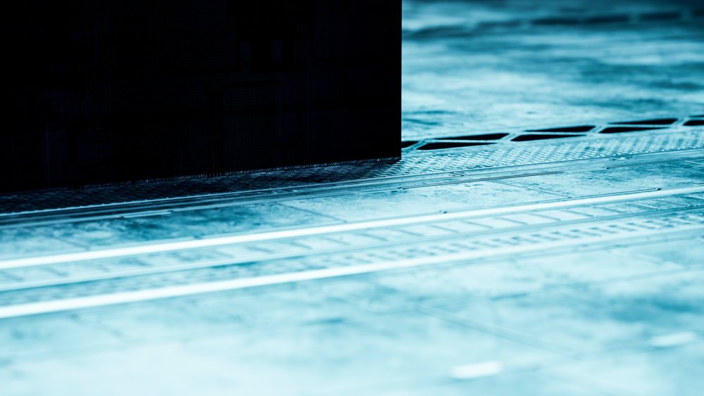 Close-up of a textured metal floor with grates and plates under blue lighting in a modern industrial setting.