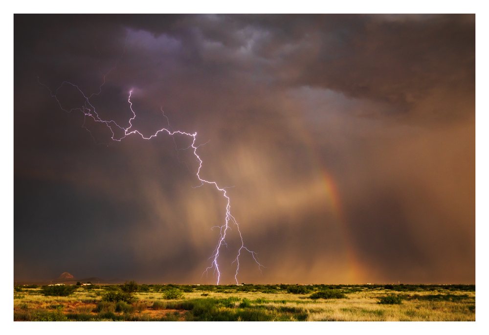 Lightning strike and a Rainbow appear above a desert landscape during a storm, Chasing, Weather, Environmental Issues, Douglas, Arizona, USA.