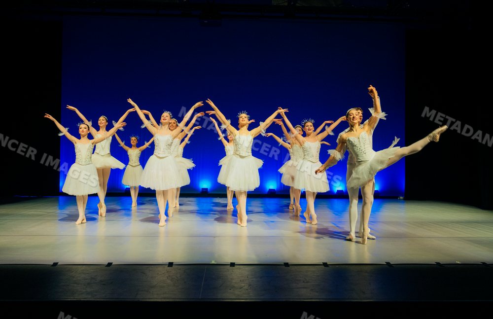 Ballet dancers perform holiday-themed dance on stage in white tutus