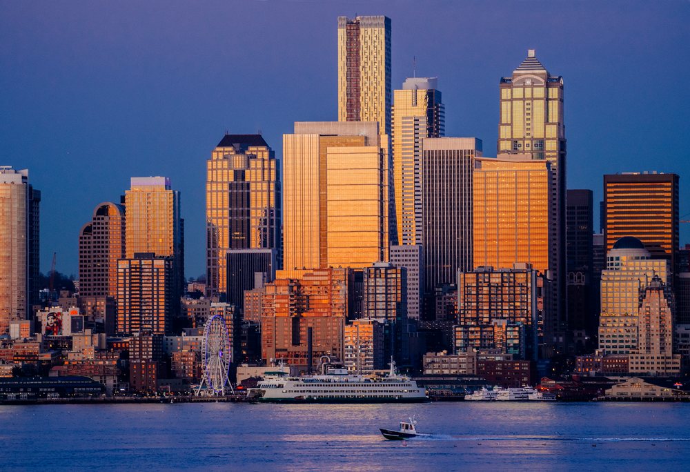 Seattle skyline at sunset with ferries, boats, and a large ferris wheel on the waterfront, WA, USA.