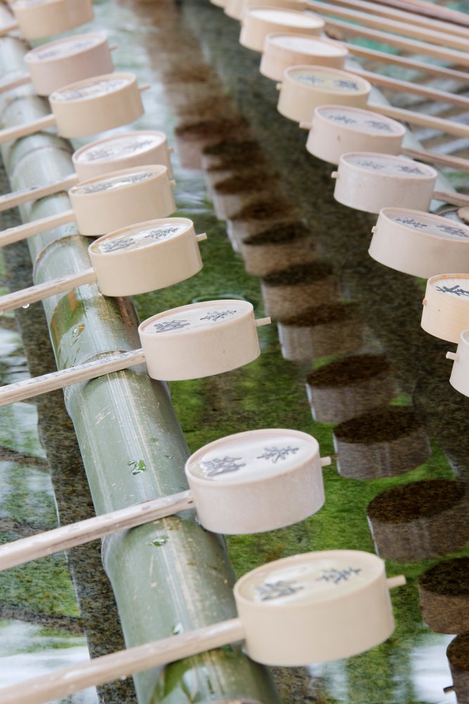 Wooden ladles resting on bamboo poles above a water basin for ritual cleansing at Fushimi Inari Shrine in Kyoto, Honshu, Japan.