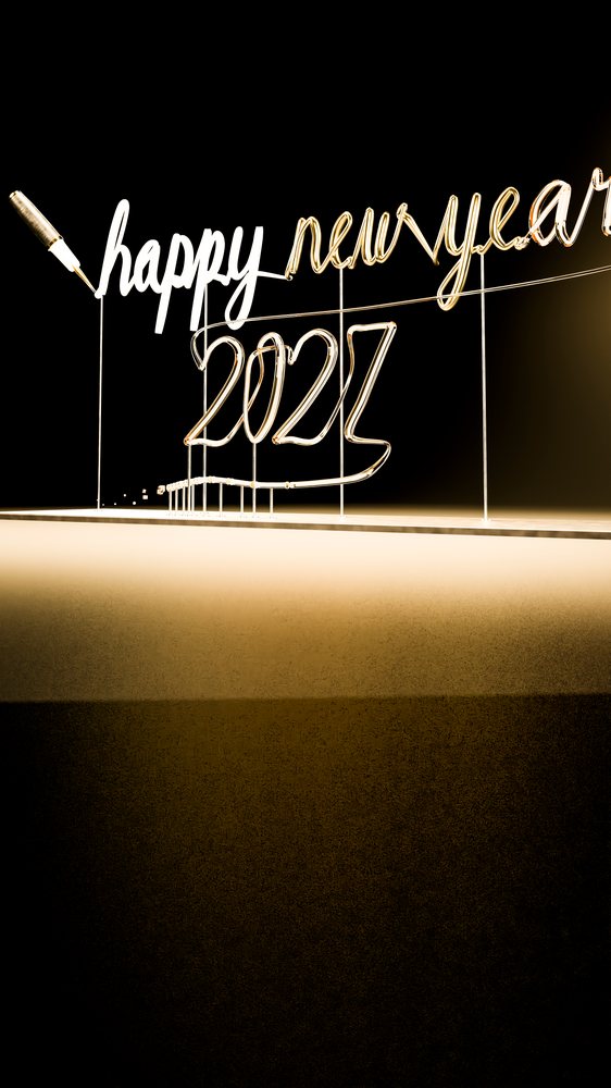 Wire sculpture forming the text 'happy new year 2023' with a pen placed at the text start against a dark background.