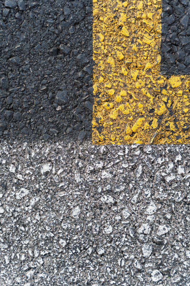 Close-up of a rough asphalt road surface with yellow and white paint markings outdoors, texture, abstract texture, background, wallpaper, Spain.