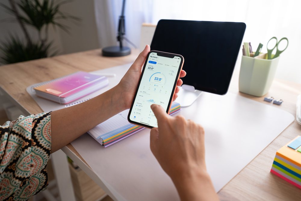 Person smartphone and interacting with app interface at a desk with office supplies and tablet in a home office, Spain.