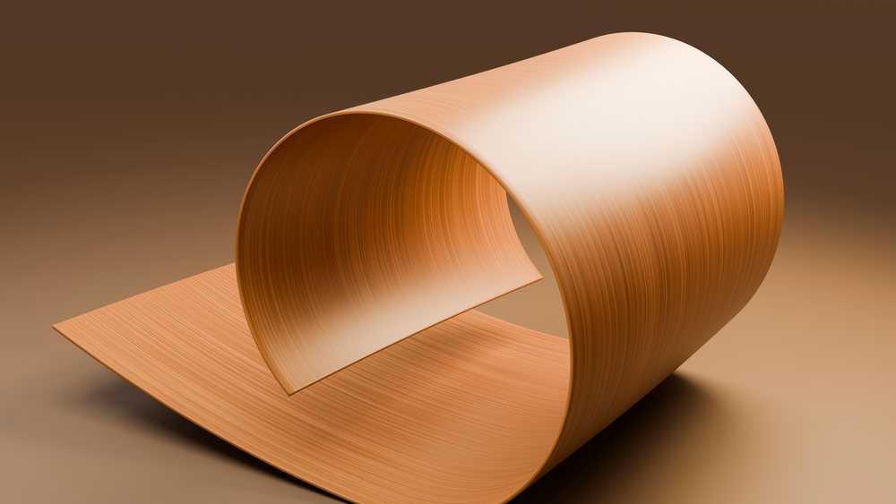 Curled wood sheet with smooth, natural grain texture forming an abstract shape on a brown background in a studio setting.