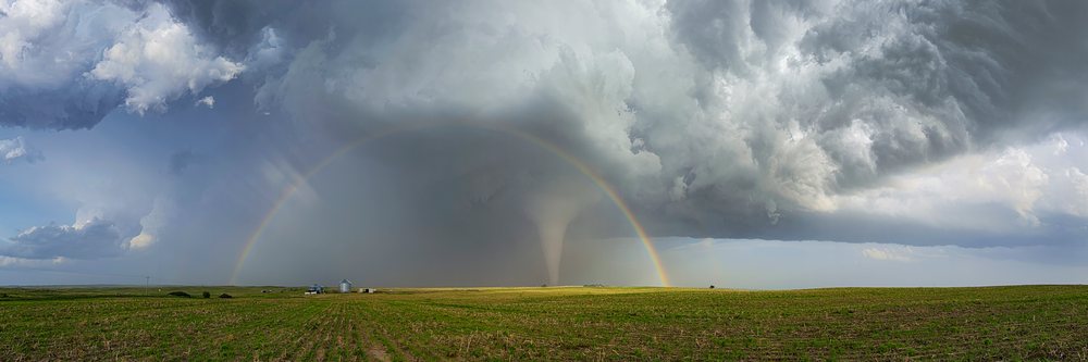 Tornado funnel cloud beneath Double Rainbow and storm clouds over a rural grain silo field, Dickens, Nebraska, USA.