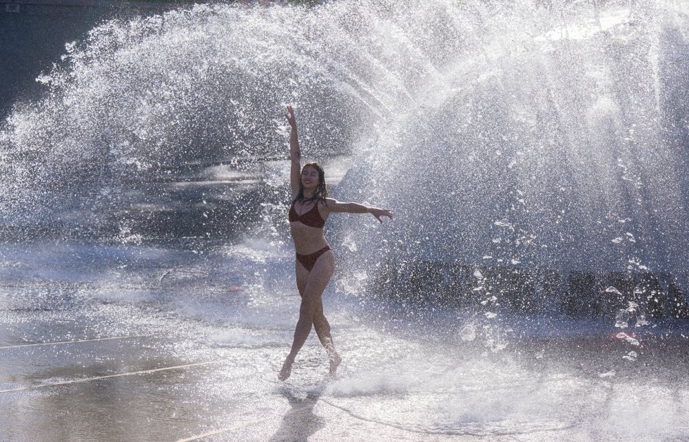 Woman jumping and dancing through splashing water outdoors in the USA, enjoying summer fun and exercise, partner, acrobatics, yoga.