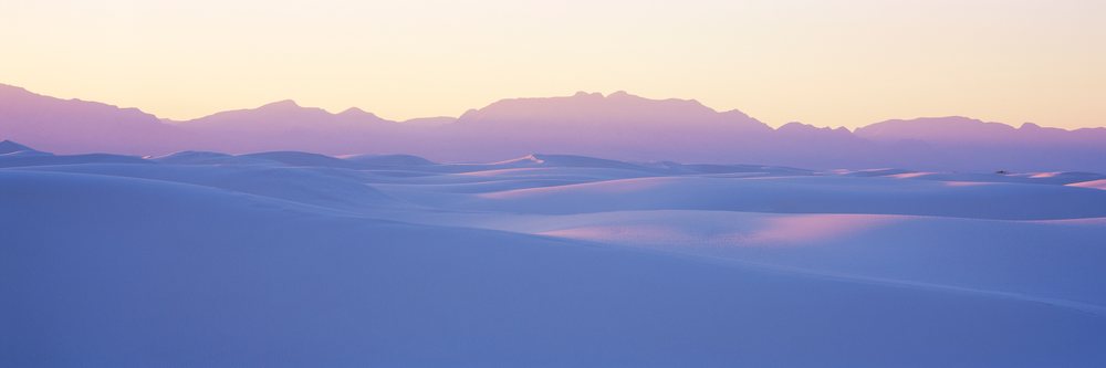 White sand dunes with mountain silhouettes at white Sands National Monument during sunset in New Mexico, white Sands New Mexico, USA.