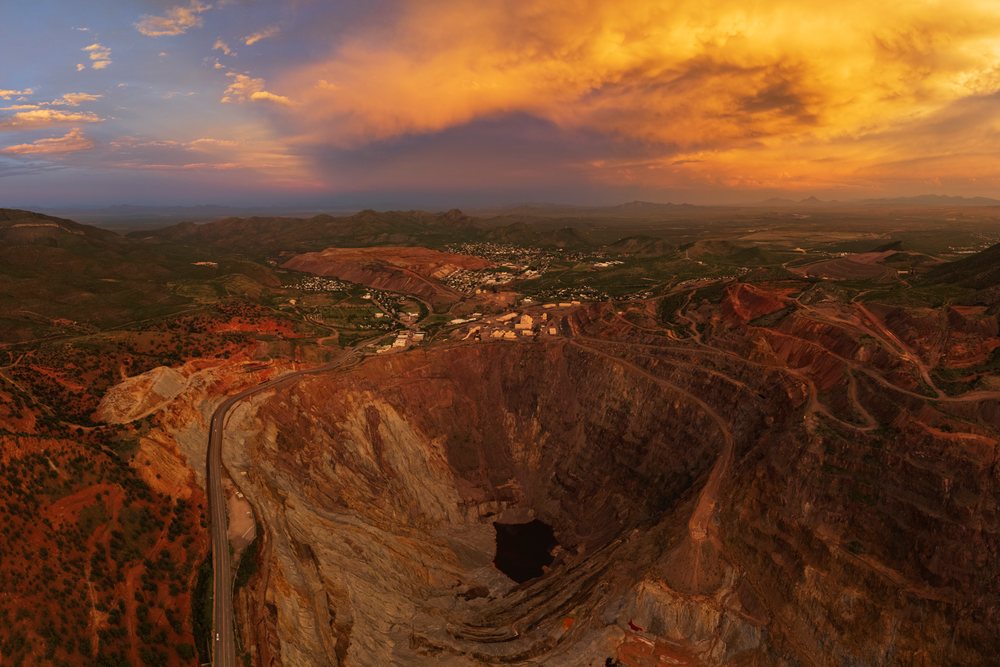 Open pit copper mine with terraced excavation and mining town near mountains under a colorful dusk sky, Storm Chasing, Weather, Environment, Bisbee, Arizona, USA.