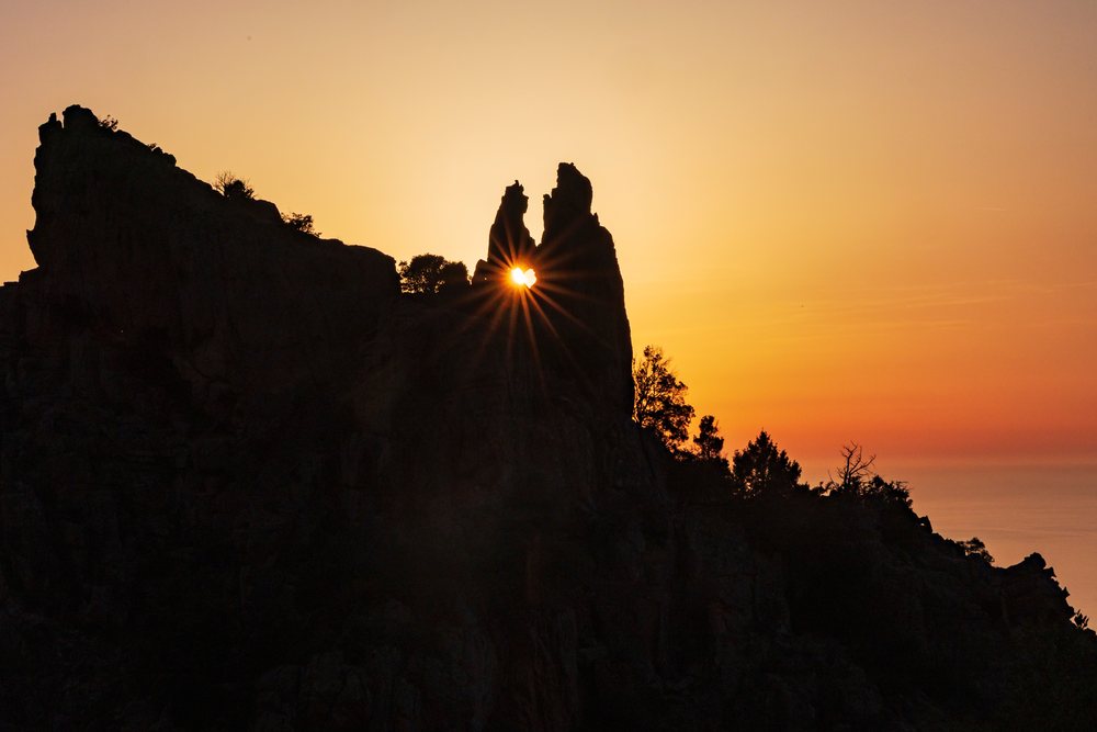 Heart-shaped rock formation with sunlight streaming through a natural hole at Sunset, Travel Photography, Piana, Corsica, France.