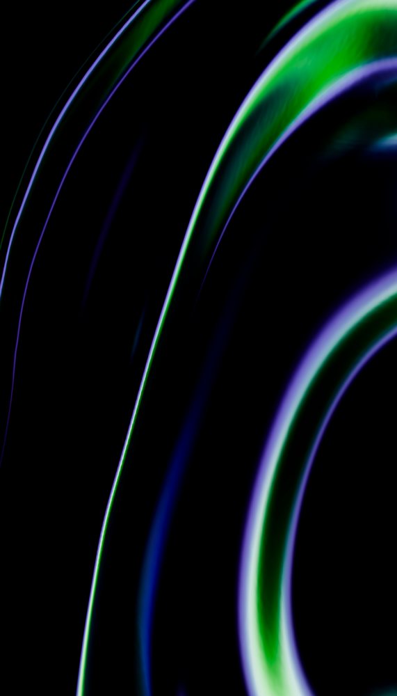 Abstract colorful curved light streaks in green and purple on a dark background forming dynamic shapes.