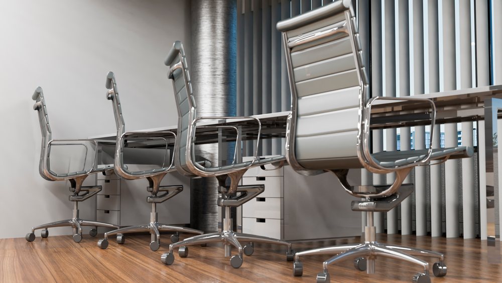 Modern conference room with four white office chairs with metal frames arranged around a wooden table.